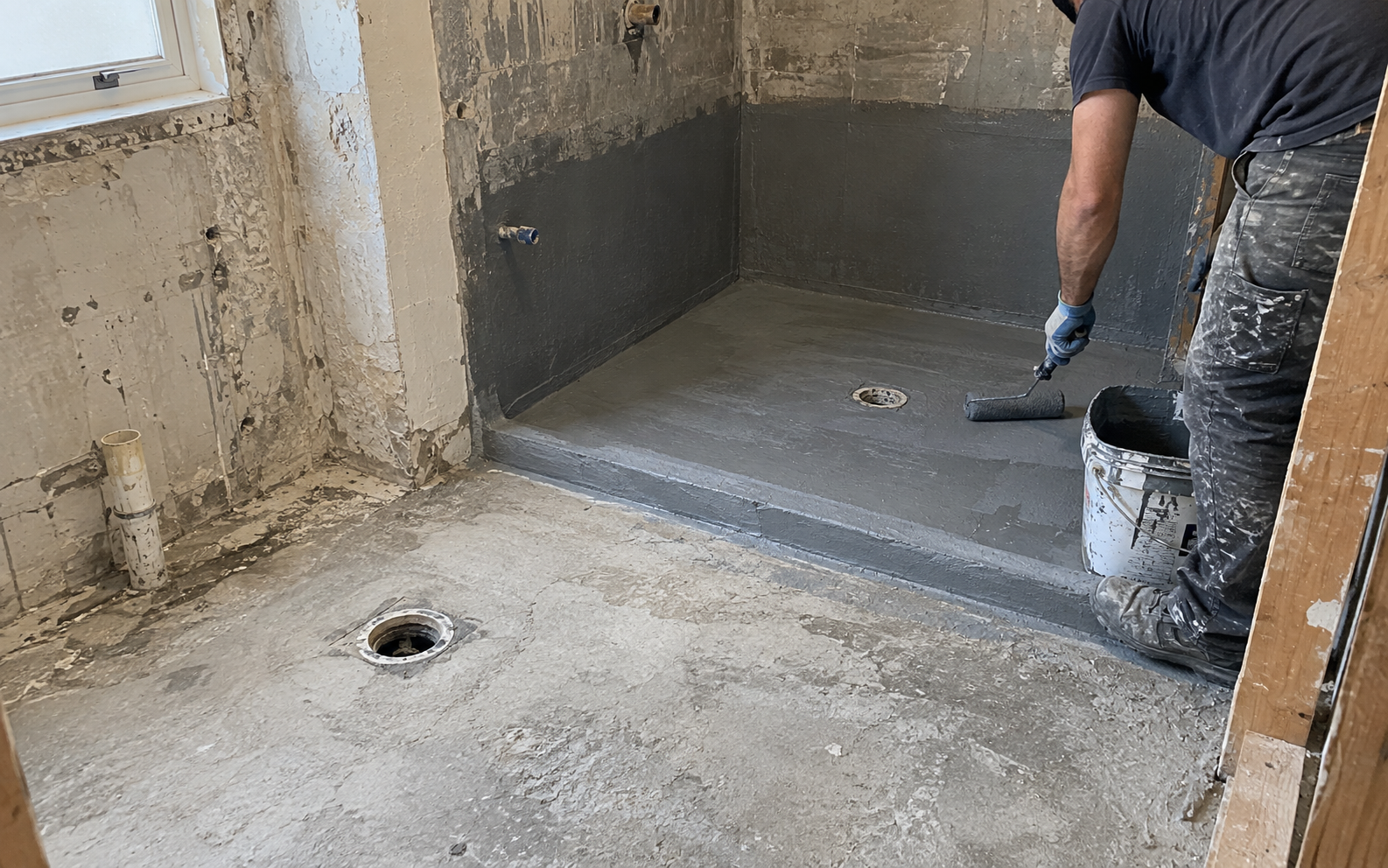 Waterproofing membrane being applied to a shower floor and wall junctions