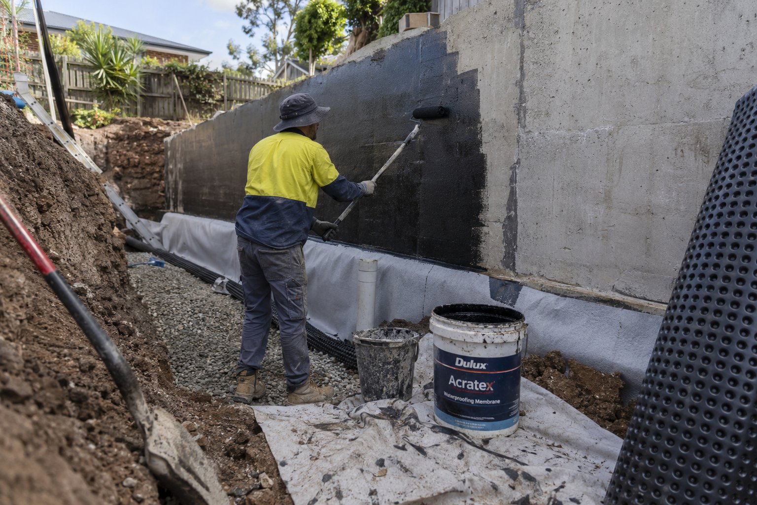 Waterproofing membrane being applied to the accessible soil-facing side of a retaining wall