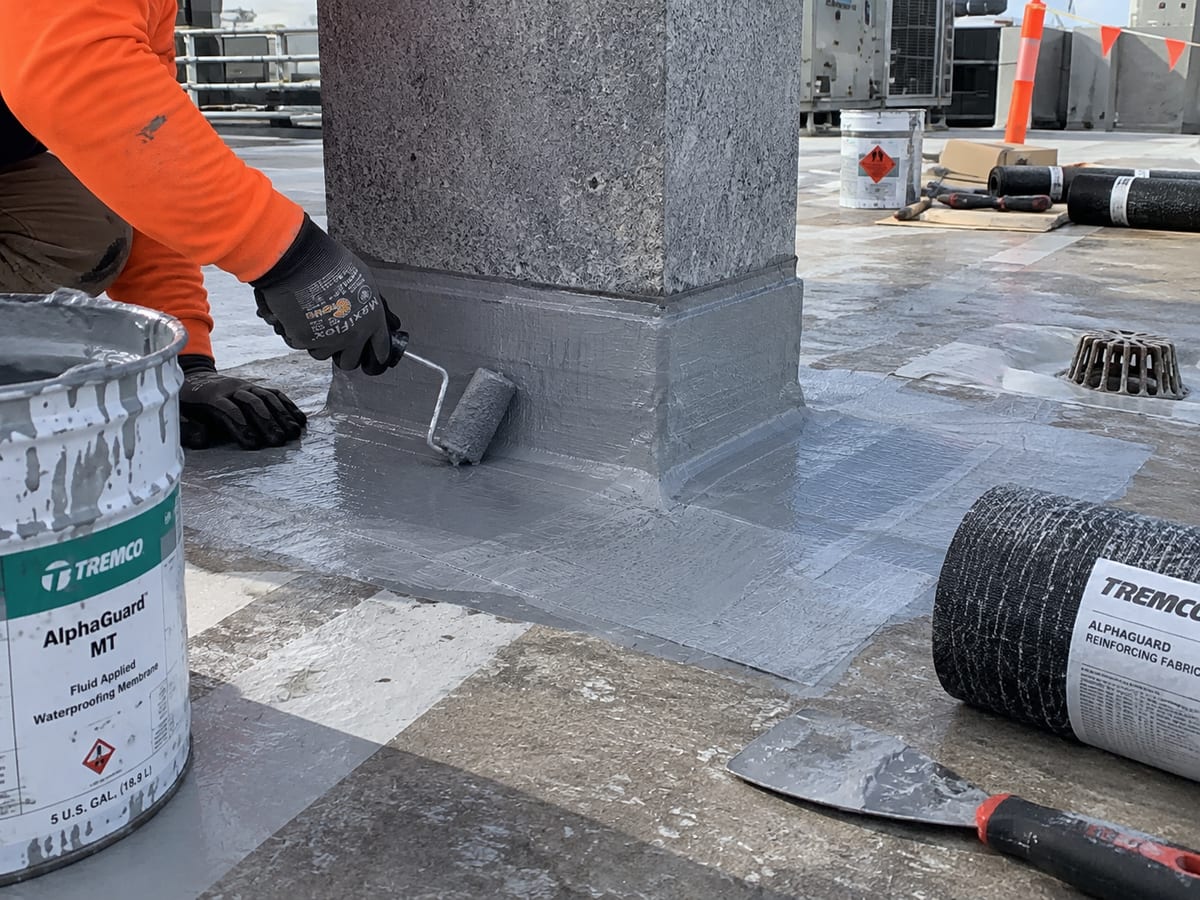 Waterproofing membrane being applied around a raised commercial roof junction