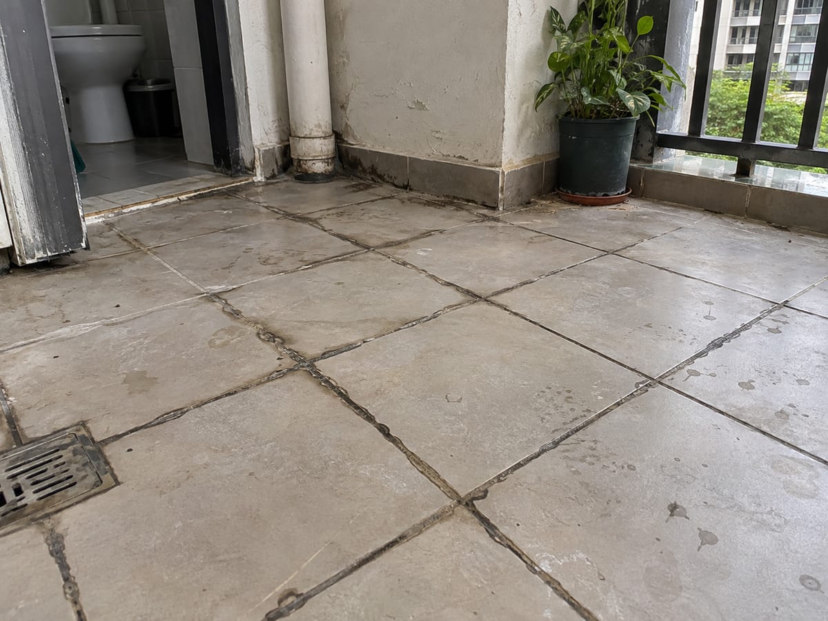 Tiled floor before regrouting with worn and open tile joints